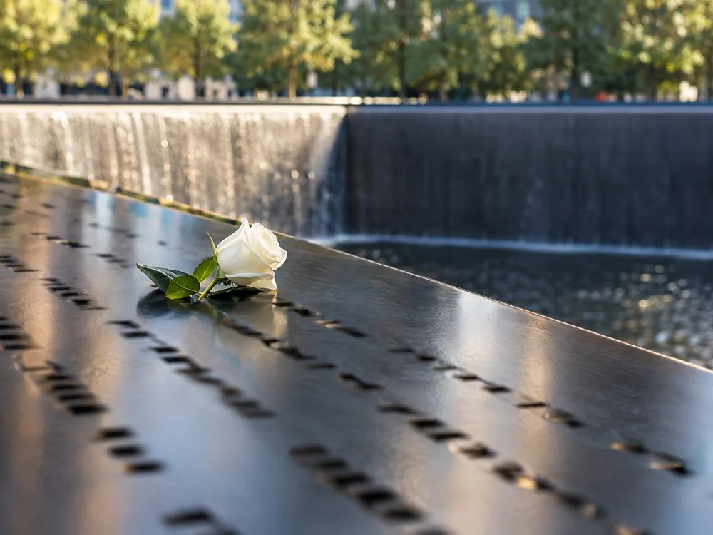 Names cut into the bronze parapet of a memorial pool with water falling beyond